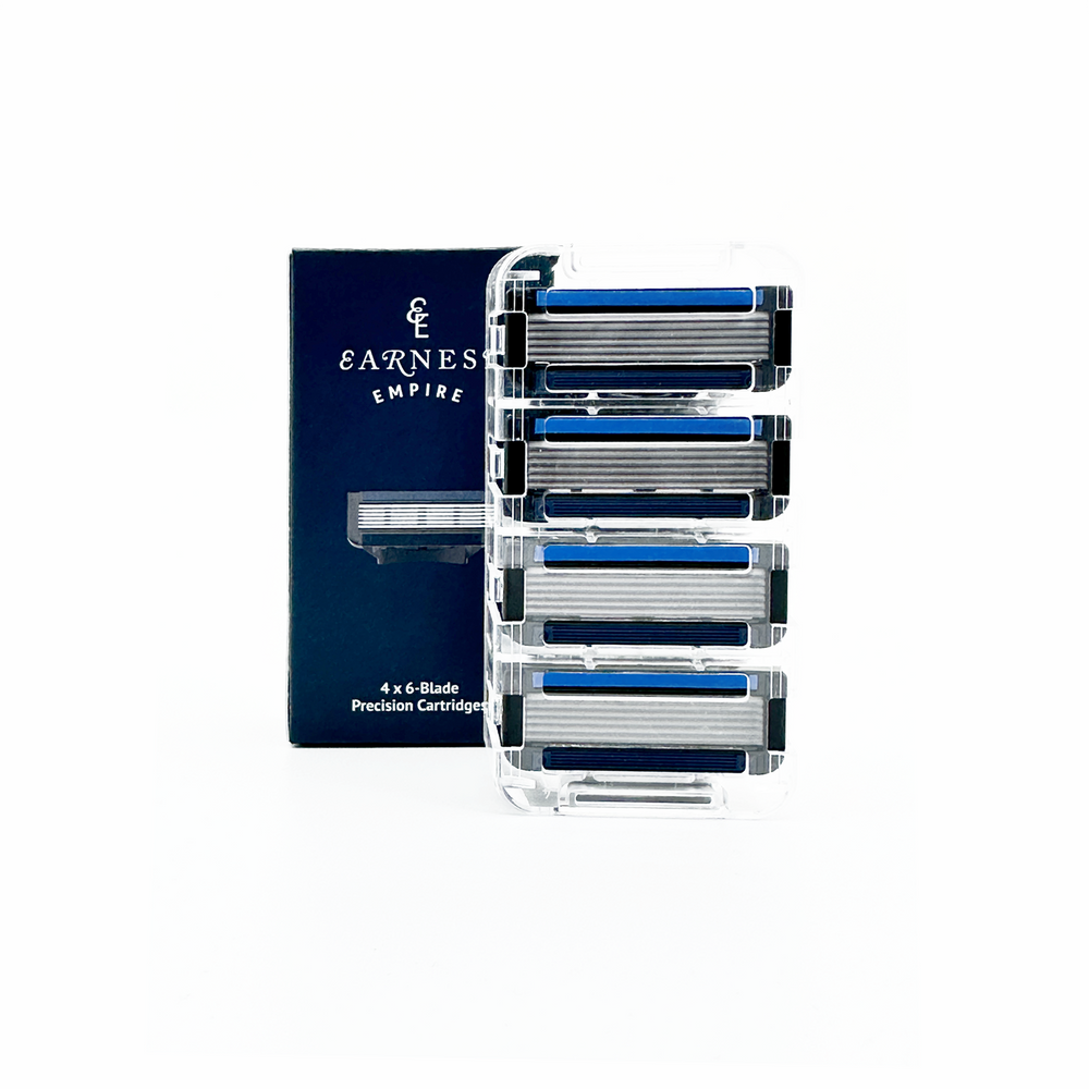 Four Earnest Empire six-blade refill cartridges in a clear holder beside their navy box.
